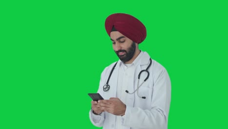 Glücklicher-Indischer-Sikh-Arzt,-Der-Eine-SMS-Mit-Grünem-Bildschirm-Schreibt