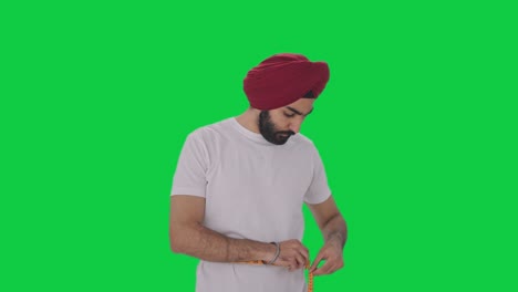 Sad-Sikh-Indian-man-measuring-waist-using-Inch-tape-Green-screen
