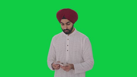 Sad-Sikh-Indian-man-counting-money-Green-screen