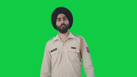 Wütender-Indischer-Sikh-Polizist,-Der-Auf-Jemanden-Zeigt-Und-Ihn-Auf-Einem-Grünen-Bildschirm-Anruft