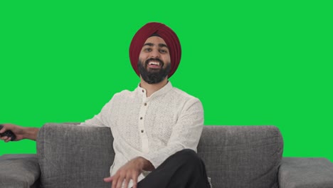 Fröhlicher-Sikh-Indianer,-Der-Lacht,-Während-Er-Fernsieht,-Grünen-Bildschirm
