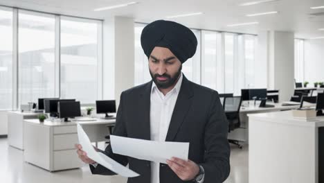 Seriöser-Indischer-Sikh-Geschäftsmann,-Der-Unternehmensberichte-Liest