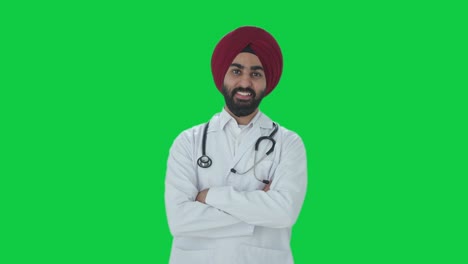 Glücklicher-Indischer-Sikh-Arzt,-Der-Mit-Gekreuzten-Händen-Auf-Grünem-Bildschirm-Steht