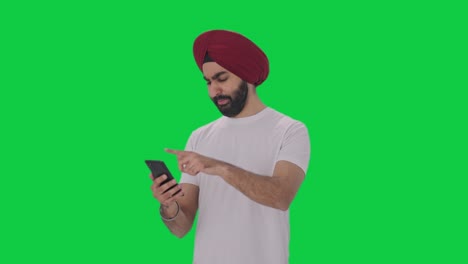 Müder-Und-Schläfriger-Sikh-Indianer,-Der-Auf-Dem-Grünen-Bildschirm-Des-Telefons-Scrollt