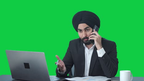 Serious-Sikh-Indian-businessman-talking-on-call-Green-screen