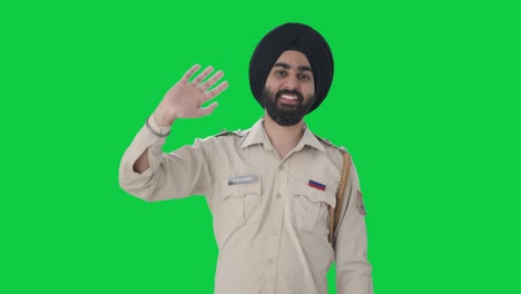 Fröhlicher-Indischer-Sikh-Polizist,-Der-„Hallo“-Auf-Grünem-Bildschirm-Sagt