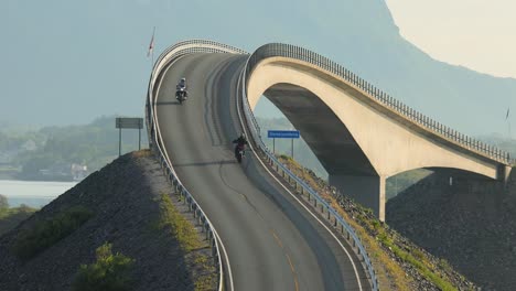 Two-motorbikers-ride-along-the-Atlantic-Ocean-Road-towards-each-other-and-greet-each-other.
