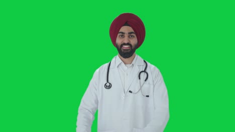 Fröhlicher-Indischer-Sikh-Arzt-Zeigt-Herzzeichen-Auf-Grünem-Bildschirm