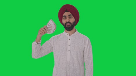 Egoistischer-Sikh-Indianer,-Der-Geld-Als-Fan-Benutzt,-Mit-Listigem-Lächeln,-Grünem-Bildschirm
