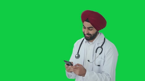 Glücklicher-Indischer-Sikh-Arzt,-Der-Jemandem-Eine-Nachricht-Auf-Grünem-Bildschirm-Sendet