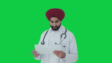 Fröhlicher-Indischer-Sikh-Arzt-überprüft-Medizinische-Berichte-Auf-Grünem-Bildschirm