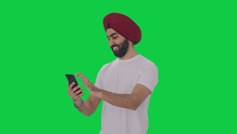 Glücklicher-Sikh-Indianer,-Der-Auf-Dem-Grünen-Bildschirm-Des-Telefons-Scrollt