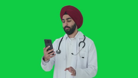 Glücklicher-Indischer-Sikh-Arzt,-Der-über-Einen-Videoanruf-Mit-Grünem-Bildschirm-Spricht