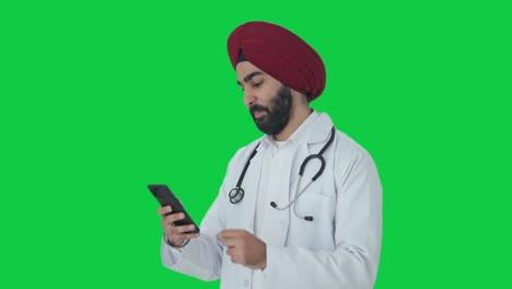 Glücklicher-Indischer-Sikh-Arzt,-Der-Den-Grünen-Bildschirm-Des-Telefons-Scrollt