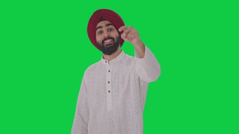 Glücklicher-Sikh-Indianer,-Der-Auf-Jemanden-Zeigt-Und-Ihn-Auf-Dem-Grünen-Bildschirm-Anruft