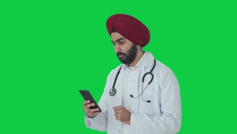Serious-Sikh-Indian-doctor-scrolling-phone-Green-screen