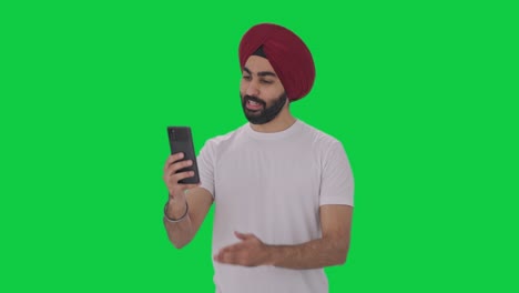 Fröhlicher-Sikh-Indianer,-Der-über-Einen-Videoanruf-Mit-Grünem-Bildschirm-Spricht