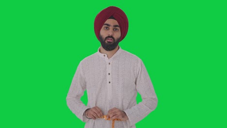Sad-Sikh-Indian-man-measuring-waist-using-inch-tape-Green-screen