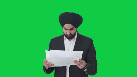 Frustrated-Sikh-Indian-businessman-reading-company-reports-Green-screen