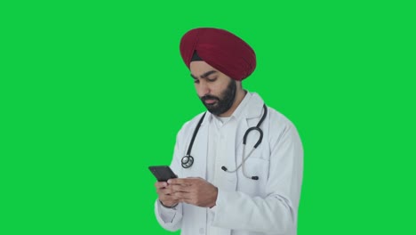 Wütender-Sikh-indischer-Arzt,-Der-Jemandem-Eine-Nachricht-Auf-Grünem-Bildschirm-Sendet