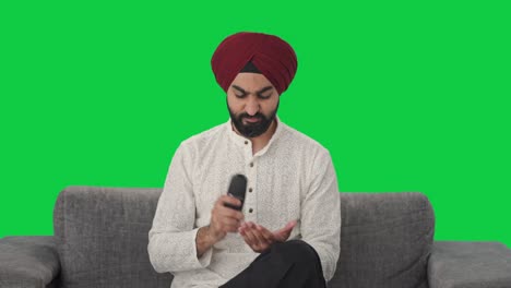 Frustrierter-Sikh-Indianer,-Der-Versucht,-Den-Grünen-Bildschirm-Der-TV-Fernbedienung-Zu-Reparieren