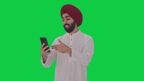 Fröhlicher-Sikh-Indianer,-Der-über-Einen-Videoanruf-Mit-Grünem-Bildschirm-Spricht
