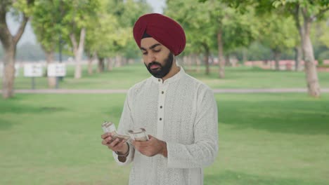 Sikh-Indian-man-counting-money-in-park