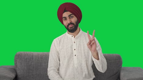 Fröhlicher-Sikh-Indianer-Zeigt-Siegeszeichen-Auf-Grünem-Bildschirm
