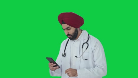 Gestresster-Indischer-Sikh-Arzt-Scrollt-Auf-Dem-Grünen-Bildschirm-Des-Telefons