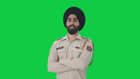 Porträt-Eines-Glücklichen-Indischen-Sikh-Polizisten,-Der-Mit-Gekreuzten-Händen-Auf-Grünem-Bildschirm-Steht