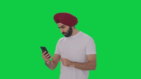 Sikh-Indischer-Mann-Scrollt-Auf-Dem-Grünen-Bildschirm-Des-Telefons