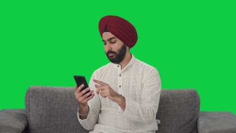 Sikh-Indian-man-scrolling-phone-Green-screen