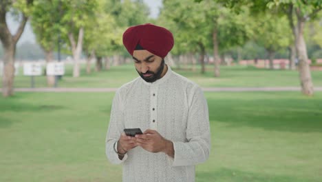 Wütender-Sikh-Indianer,-Der-Jemandem-Im-Park-Eine-SMS-Schreibt