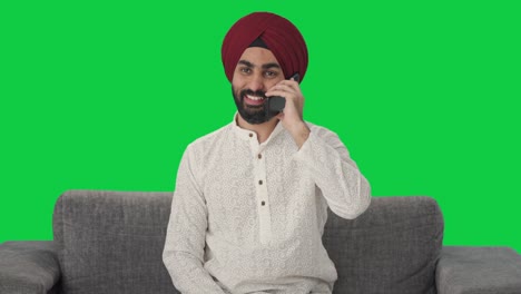 Fröhlicher-Sikh-Indianer,-Der-Auf-Dem-Grünen-Bildschirm-Des-Telefons-Spricht