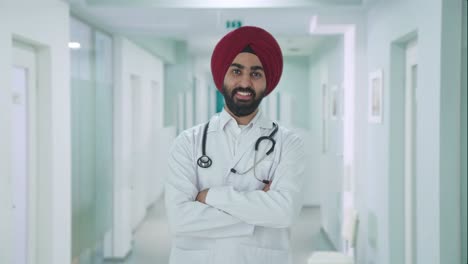 Glücklicher-Indischer-Sikh-Arzt,-Der-Mit-Gekreuzten-Händen-Steht