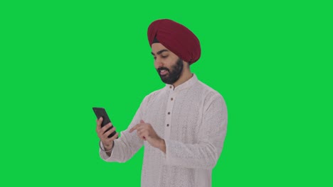 Glücklicher-Sikh-Indianer,-Der-Den-Grünen-Bildschirm-Des-Telefons-Benutzt