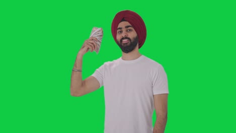 Sikh-Indianer,-Der-Geld-Als-Fan-In-Grüner-Haltung-Verwendet