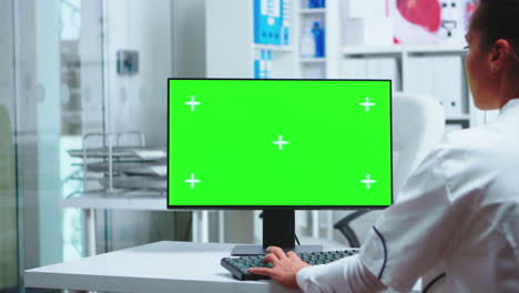 Female-doctor-working-on-green-screen-PC