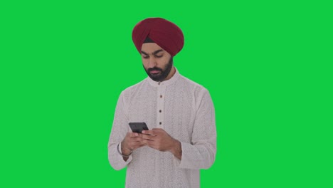 Sikh-Indian-man-texting-someone-Green-screen