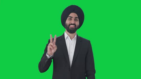 Fröhlicher-Indischer-Sikh-Geschäftsmann-Zeigt-Siegeszeichen-Auf-Grünem-Bildschirm