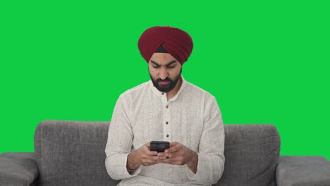 Wütender-Sikh-Indianer,-Der-Jemandem-Eine-Nachricht-Auf-Grünem-Bildschirm-Sendet