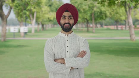 Glücklicher-Sikh-Indianer,-Der-Mit-Gekreuzten-Händen-Im-Park-Steht