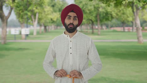 Sad-Sikh-Indian-man-measuring-waist-using-inch-tape-in-park