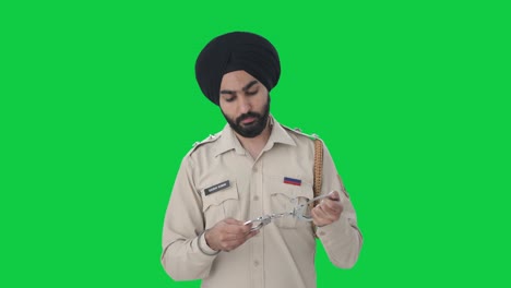 Sikh-Indian-police-man-checking-handcuffs-Green-screen