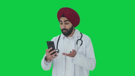 Médico-Indio-Sikh-Enojado-Hablando-En-Videollamada-En-Pantalla-Verde