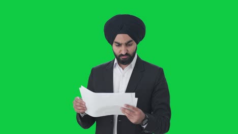 Stressed-Sikh-Indian-businessman-reading-company-reports-Green-screen