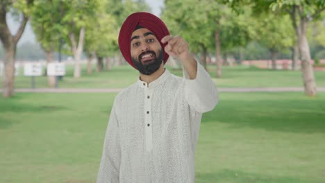 Glücklicher-Sikh-Indianer,-Der-Im-Park-Auf-Jemanden-Zeigt-Und-Ihn-Anruft