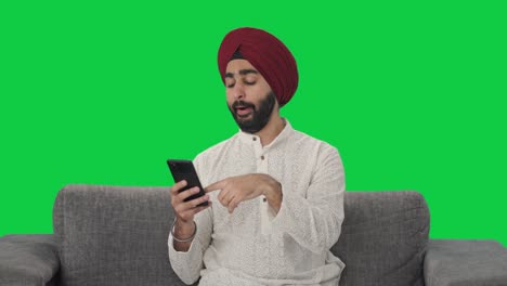 Fauler-Sikh-Indianer,-Der-Auf-Dem-Grünen-Bildschirm-Des-Telefons-Scrollt