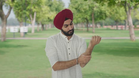 Hombre-Indio-Sikh-Enfermo-Que-Sufre-De-Dolor-En-La-Mano-En-El-Parque