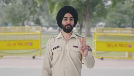 Fröhlicher-Indischer-Sikh-Polizist-Zeigt-Siegeszeichen